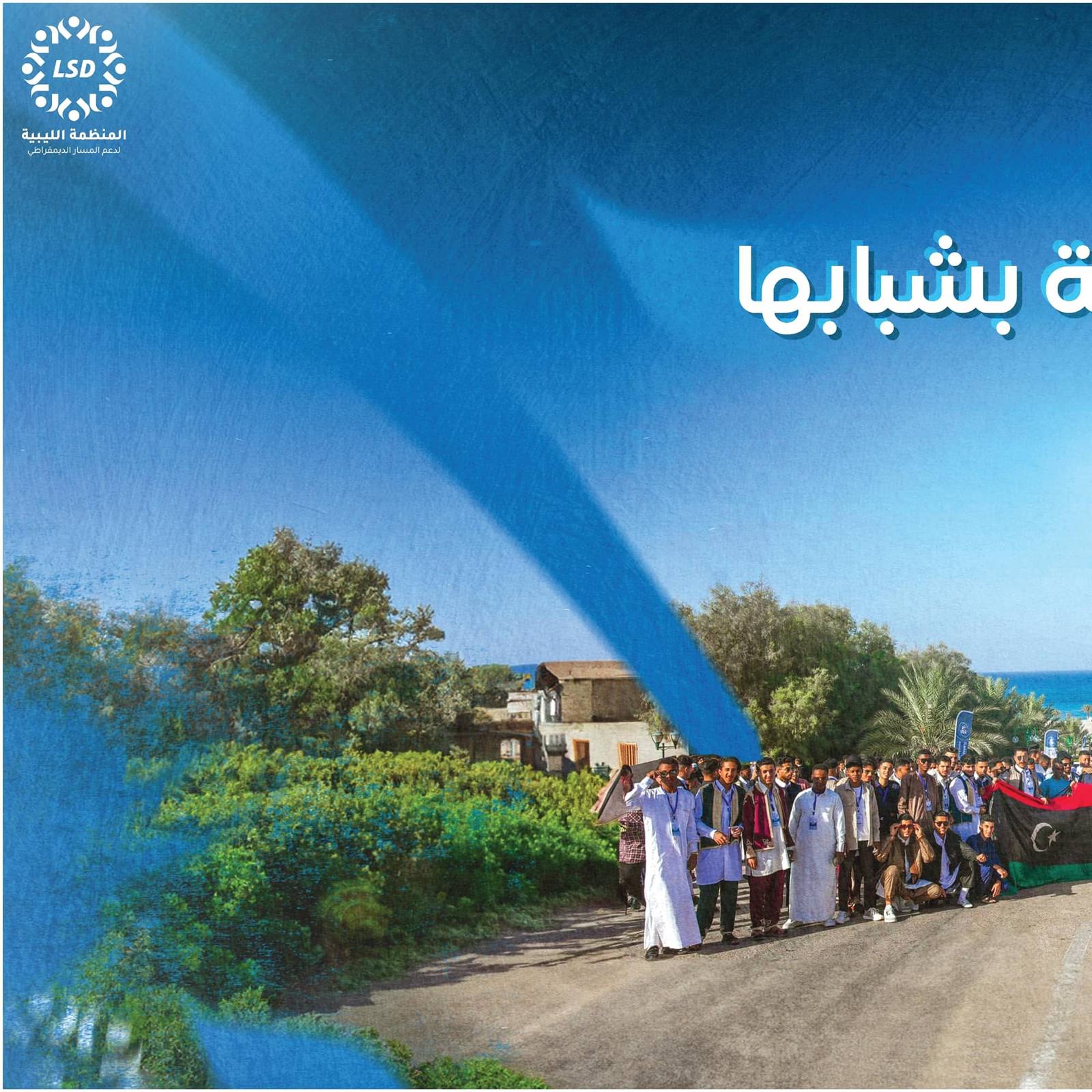 Forum participants by the Misurata seafront — left half of the 'Libya, radiant with its youth' banner