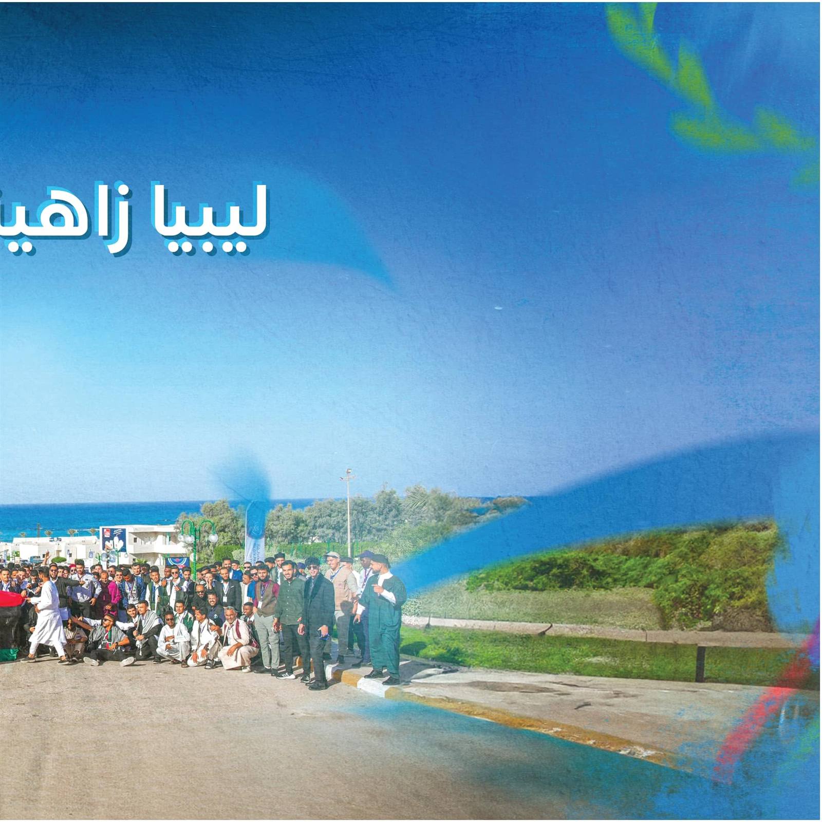 Forum participants by the Misurata seafront — right half of the 'Libya, radiant with its youth' banner